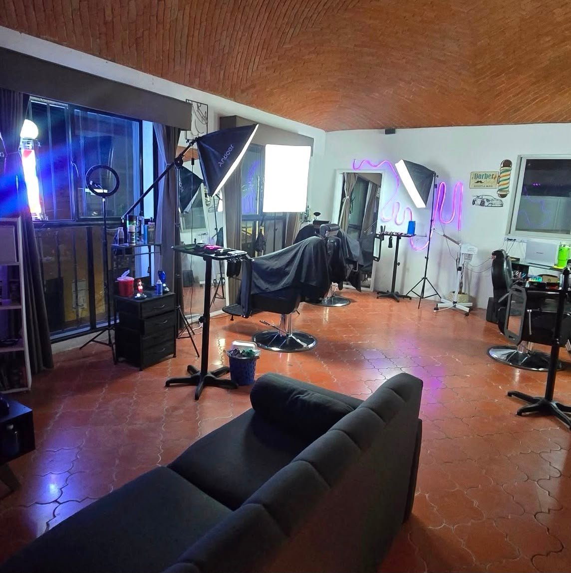Interior del estudio Aesthetic Barber Studio con luces neón, sillas de barbero y sala lounge